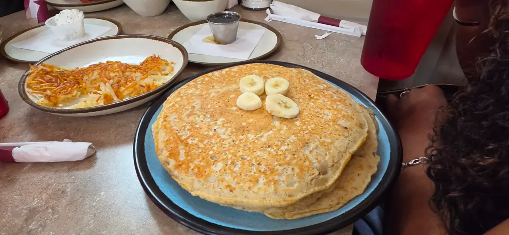 Johnny Cake cornbread pancakes with sliced banana and hash browns on the counter at 43rd Street Deli