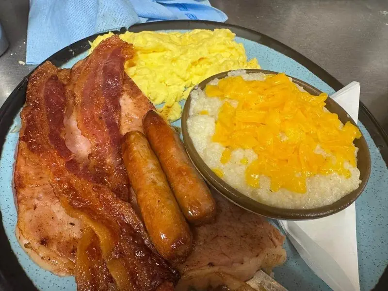 Bacon, breakfast sausage links, scrambled eggs and cheese grits at 43rd Street Deli